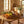 Basket with oranges, lemons, grapes, artichokes, and bread on a wooden table in a sunlit kitchen.
