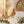 Wooden brush with bristles, water dripping, eucalyptus leaves, and stones on a marble surface.
