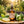 Brown glass spray bottle with lemons, basil, and bergamot on a wooden surface, sunlight in background.