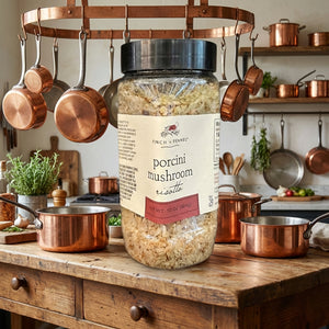 Jar of porcini mushroom risotto on a rustic kitchen counter with hanging copper pots.