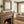 Cozy living room with stone fireplace, wooden mantel, bird sculptures, beige sofa, and plaid pillows.