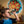 Boy looking through kaleidoscope projecting colorful pattern on wall; wearing a blue shirt.