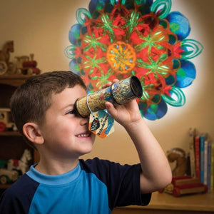Boy looking through kaleidoscope projecting colorful pattern on wall; wearing a blue shirt.