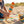 Child playing with a wooden toy on a sandy beach, colorful striped blanket, and a beach bucket nearby.