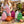Woman in white T-shirt with colorful quilted backpacks on a table; pink, orange, green, and white.