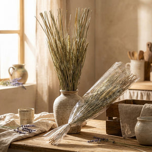 A vase of tall dried grass on a wooden table with lavender, in warm, natural light.