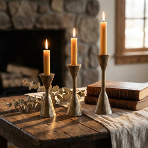 Set of three hand-forged iron candle holders with antique brass finish, designed for taper candles.