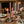 Pink candles in brass holders on a wooden table with roses, eucalyptus, and elegant tableware.