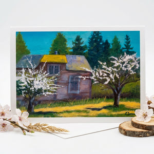 A rustic house with a yellow roof, surrounded by blooming trees and a grassy field under a blue sky.