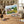 Painting of a countryside scene on a table, surrounded by art supplies and rustic kitchenware.