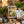 Art display with vibrant landscape painting, surrounded by plants, mugs, baskets, and notebooks.