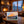 Cozy cabin with stone fireplace, warm fire, snowy mountain view, and a colorful landscape painting.