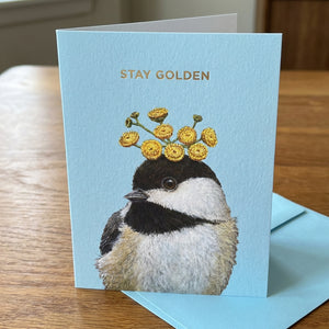 Card with a bird wearing yellow flowers on its head, text "Stay Golden" on blue background.