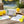 Notes and pickleball items on a wooden table near a court. Bright yellow balls and vibrant cards.