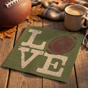 Green napkin with "LOVE" text, a football design, next to a cup of coffee and autumn leaves.