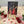 Card with two cardinals on a wooden stand, surrounded by red and pink roses and heart shapes.
