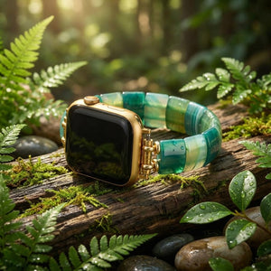 Gold smartwatch with green band on mossy log in a sunlit forest setting.