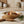 Olives and cherry tomatoes in a tan dish with toothpicks, on a wooden board, rosemary on cloth.