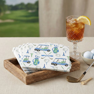 Golf-themed napkins in a wooden tray, iced tea with lemon slice, golf balls, and a club on a table.