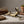 Bronze rabbit sculpture on a linen surface, surrounded by old books and a terracotta plant pot.