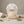 Beige silicone bib with packaging, surrounded by rolled cloths, wooden spoon, and teething rings.