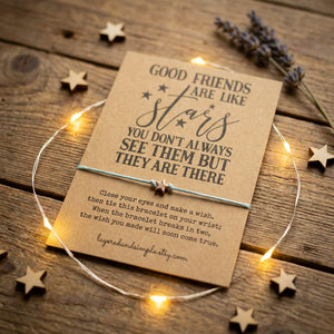 Brown card with star-themed text, a bracelet, surrounded by fairy lights on wooden surface.