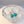 Silver earrings with turquoise stones in a clear glass bowl on a white surface.